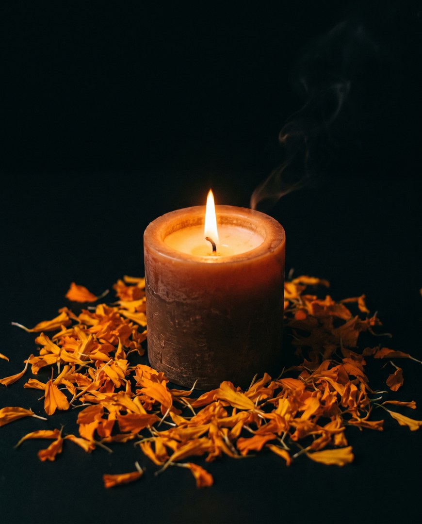 Vela de soya encendida sobre pétalos de cempasúchil
